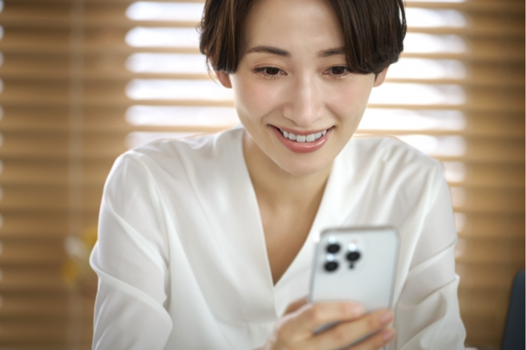 スマートフォンを笑顔で見つめる女性